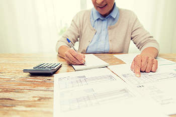 senior woman with papers and calculator at home