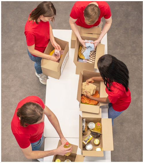 Four people packing food and clothing into donation boxes