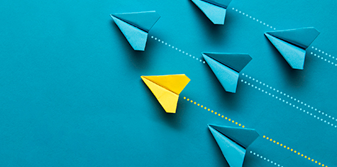 Group of blue paper airplanes and one yellow paper airplane in upward trajectory