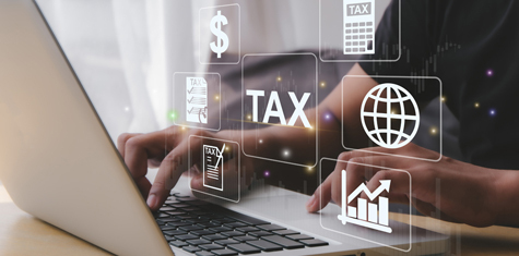 Various tax icons hovering over a pair of hands typing on a laptop